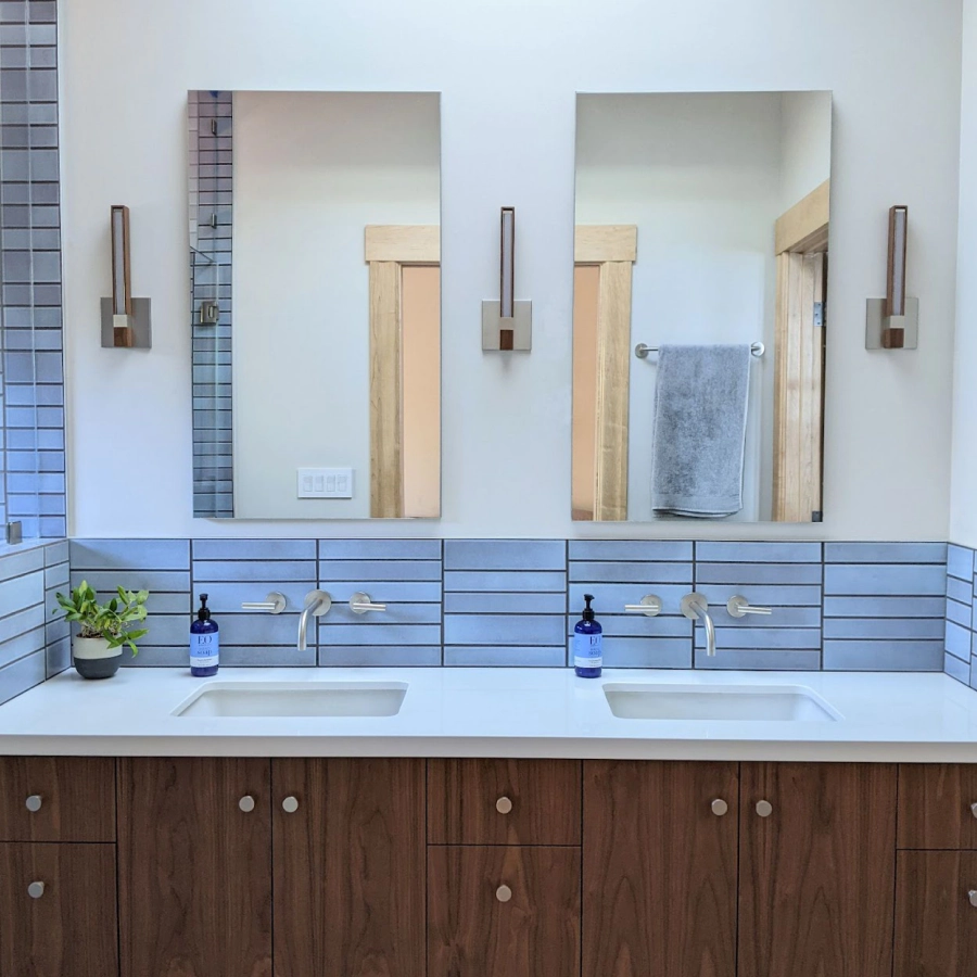 Double vanity backsplash of blue handmade tile, each column a different mix of 2-inch and 3-inch rows, with wall-mounted faucets set to the tile