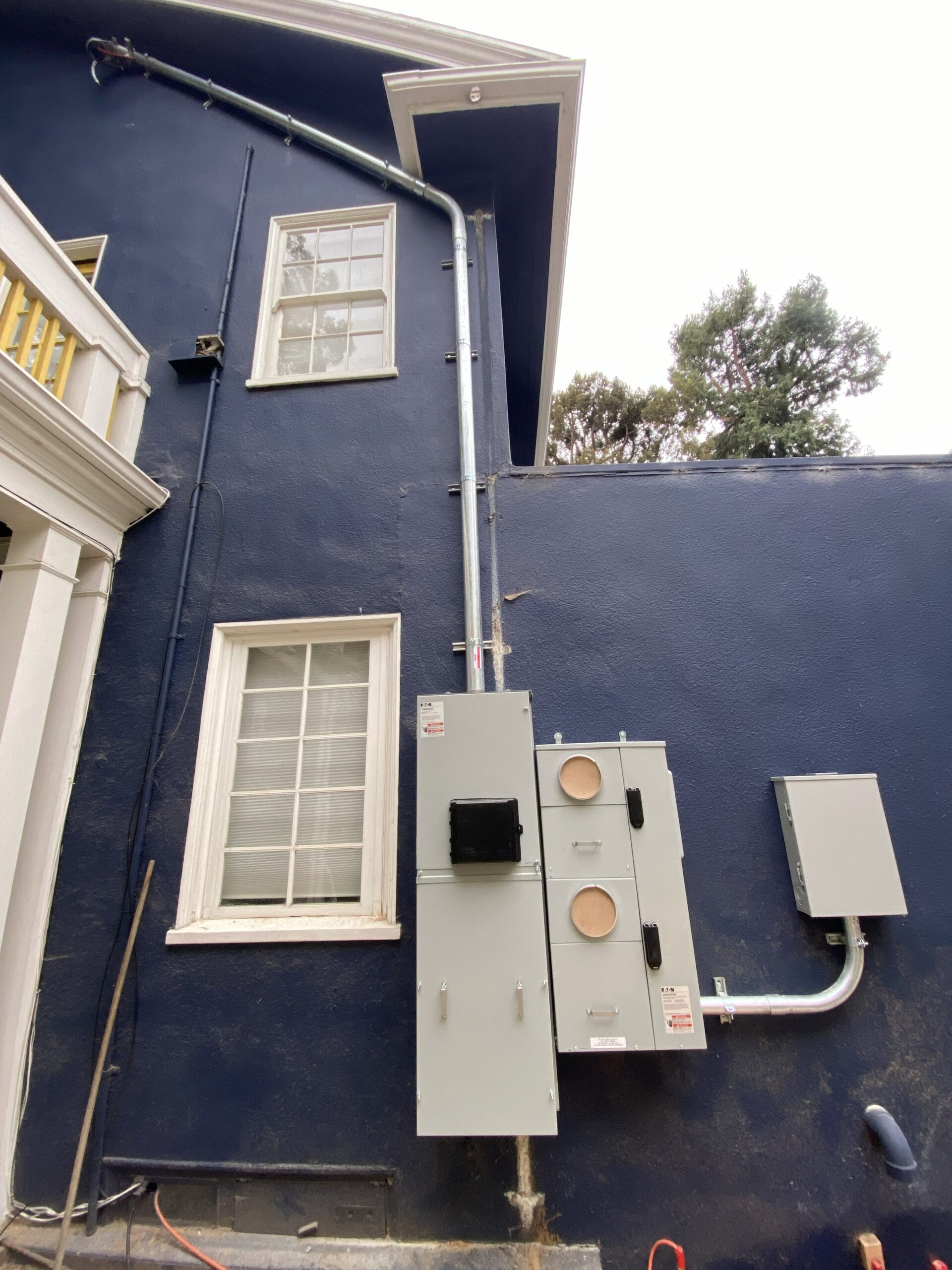 New 400-amp PG&E service upgrade on the side of the Adams Point house, with conduit running up the wall and along the roofline to the weatherhead