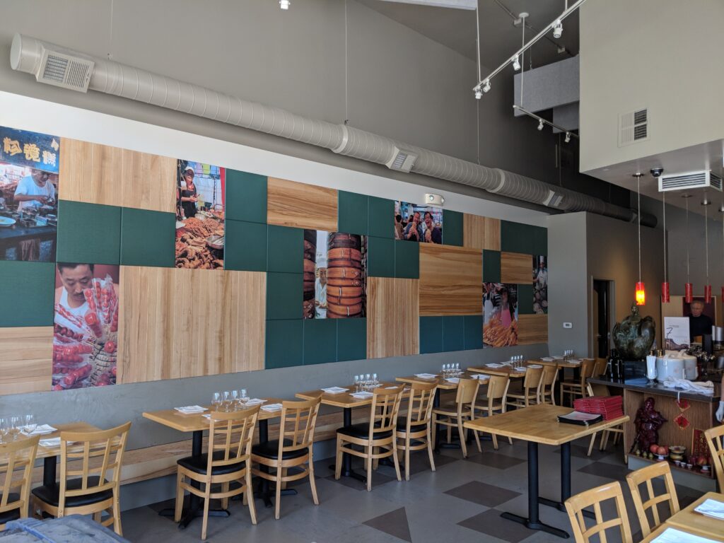 Dining room at Lin Jia Asian Kitchen in Oakland, with a 30-foot accent wall of hardwood panels, green acoustic panels and street food photos