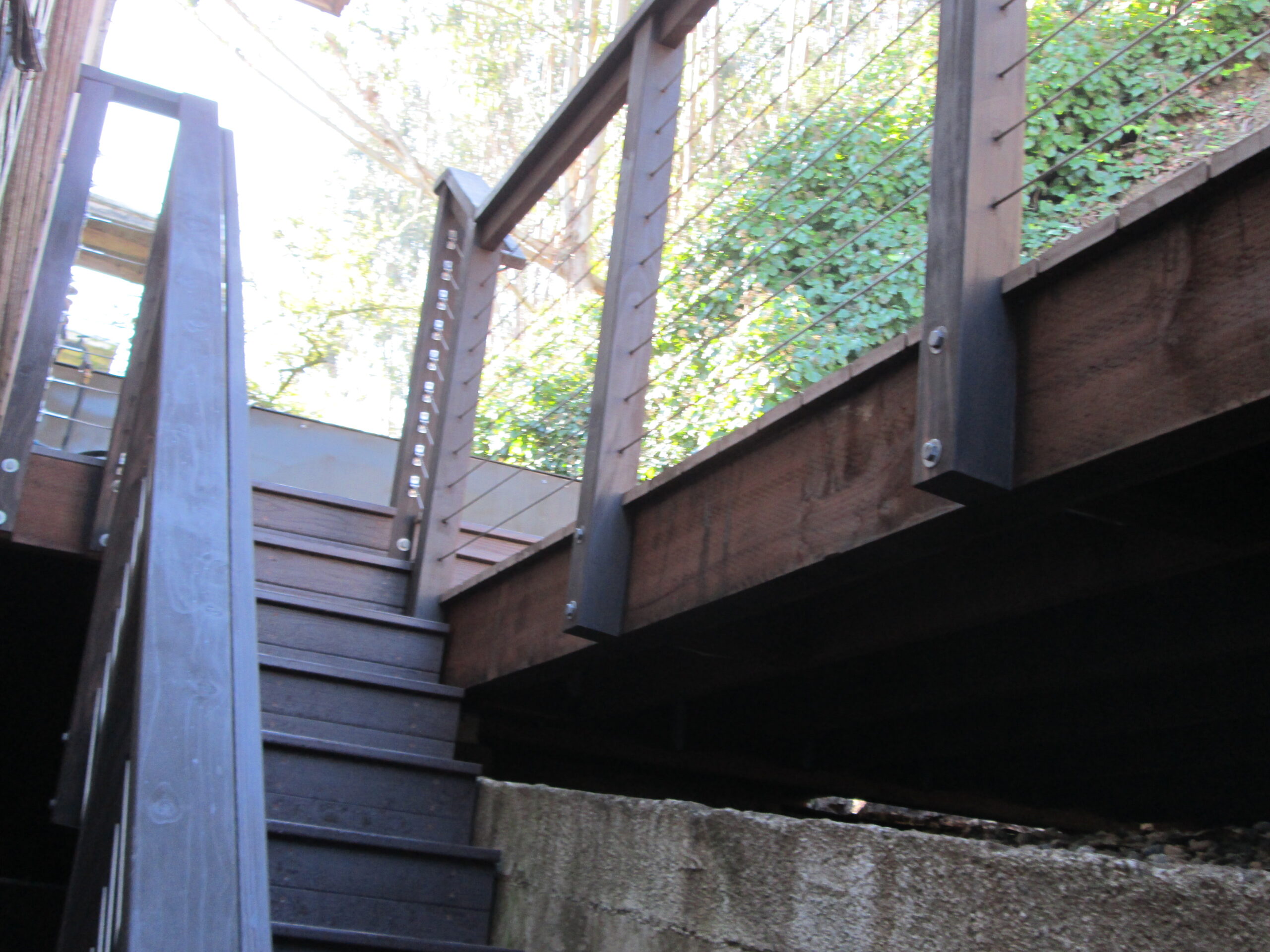 Deck stairs with stainless steel cable railing and dark-stained redwood posts