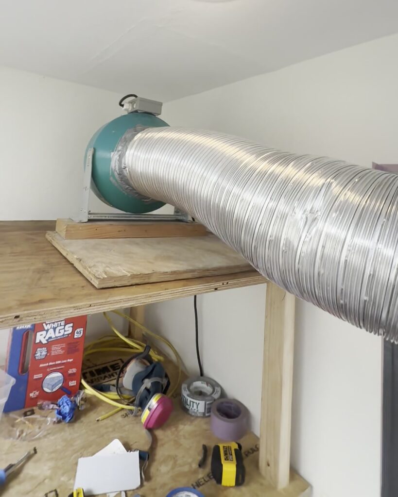 A fan on a shelf in the upstairs hallway, pushing clean air through a duct into the bathroom under construction