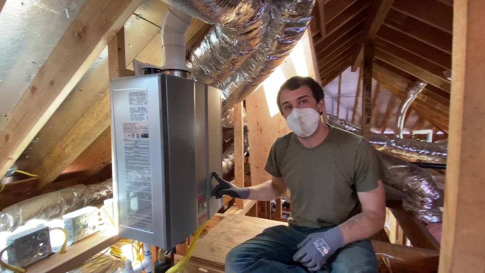 Alex Pell in the attic of a Piedmont addition next to the tankless water heater, where keeping plumbing in the crawl space would have avoided water hammer
